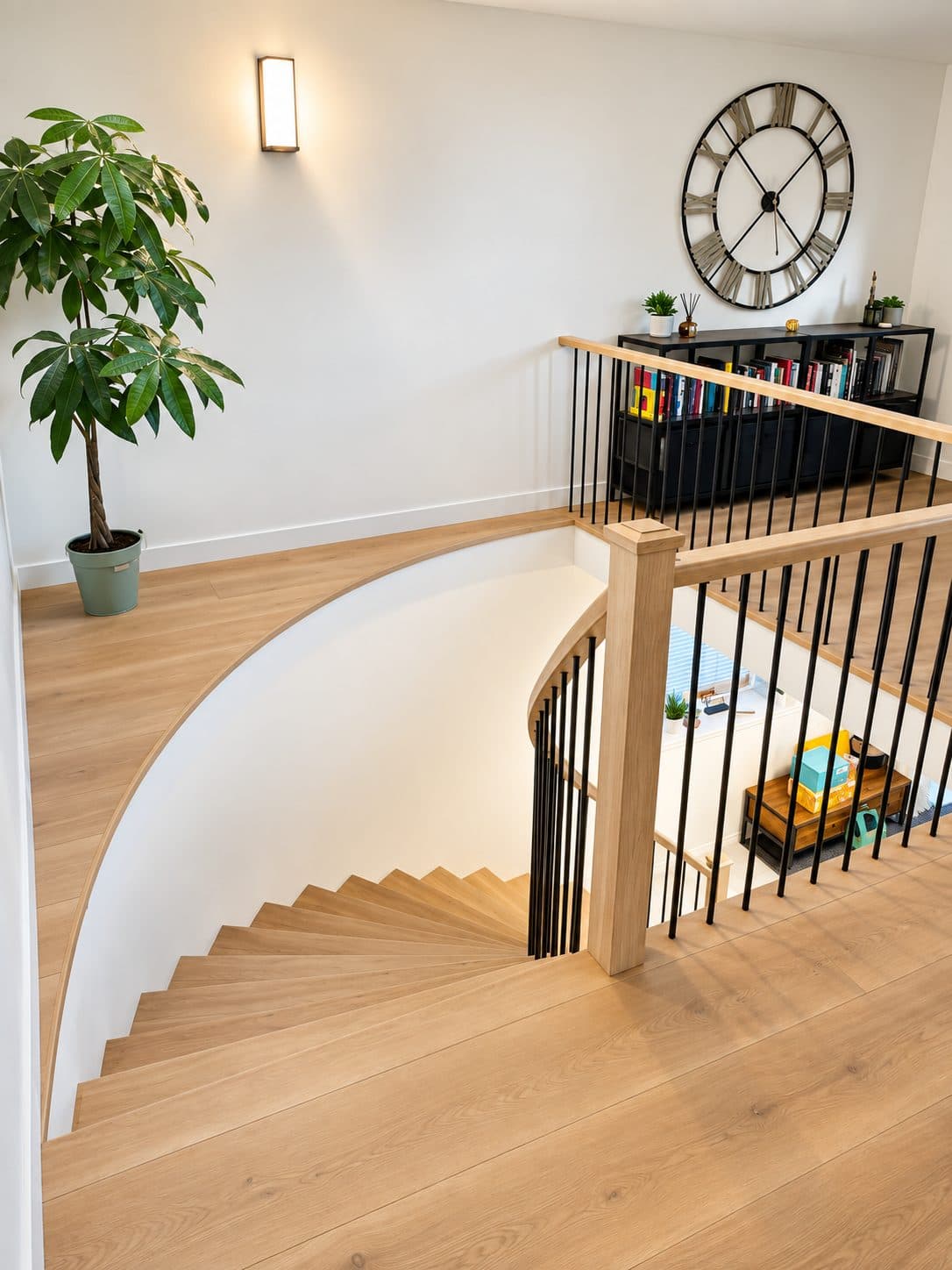 Curved staircase with light wood treads, seen from the landing above