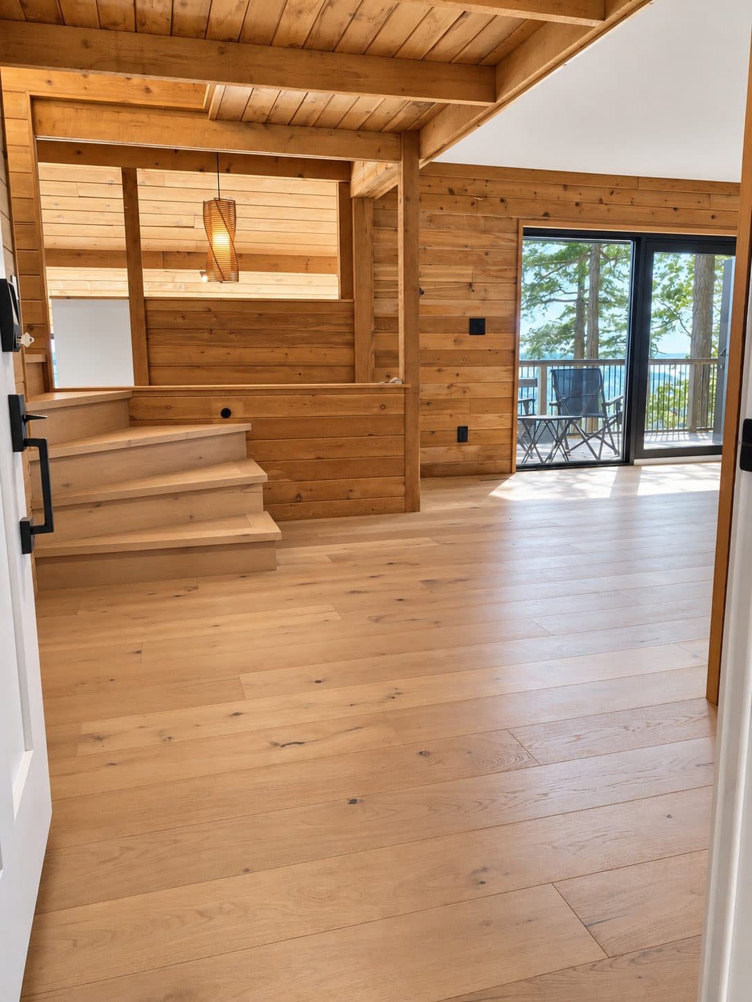 Open room with a light wood floor under cedar walls and ceiling