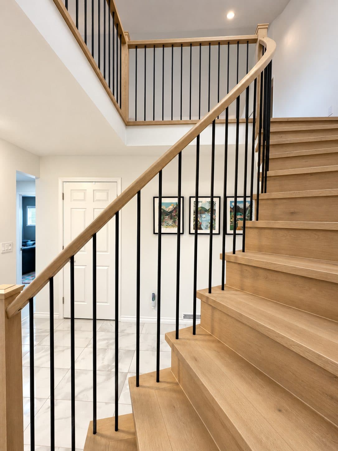 Curved staircase with light wood treads and black balusters