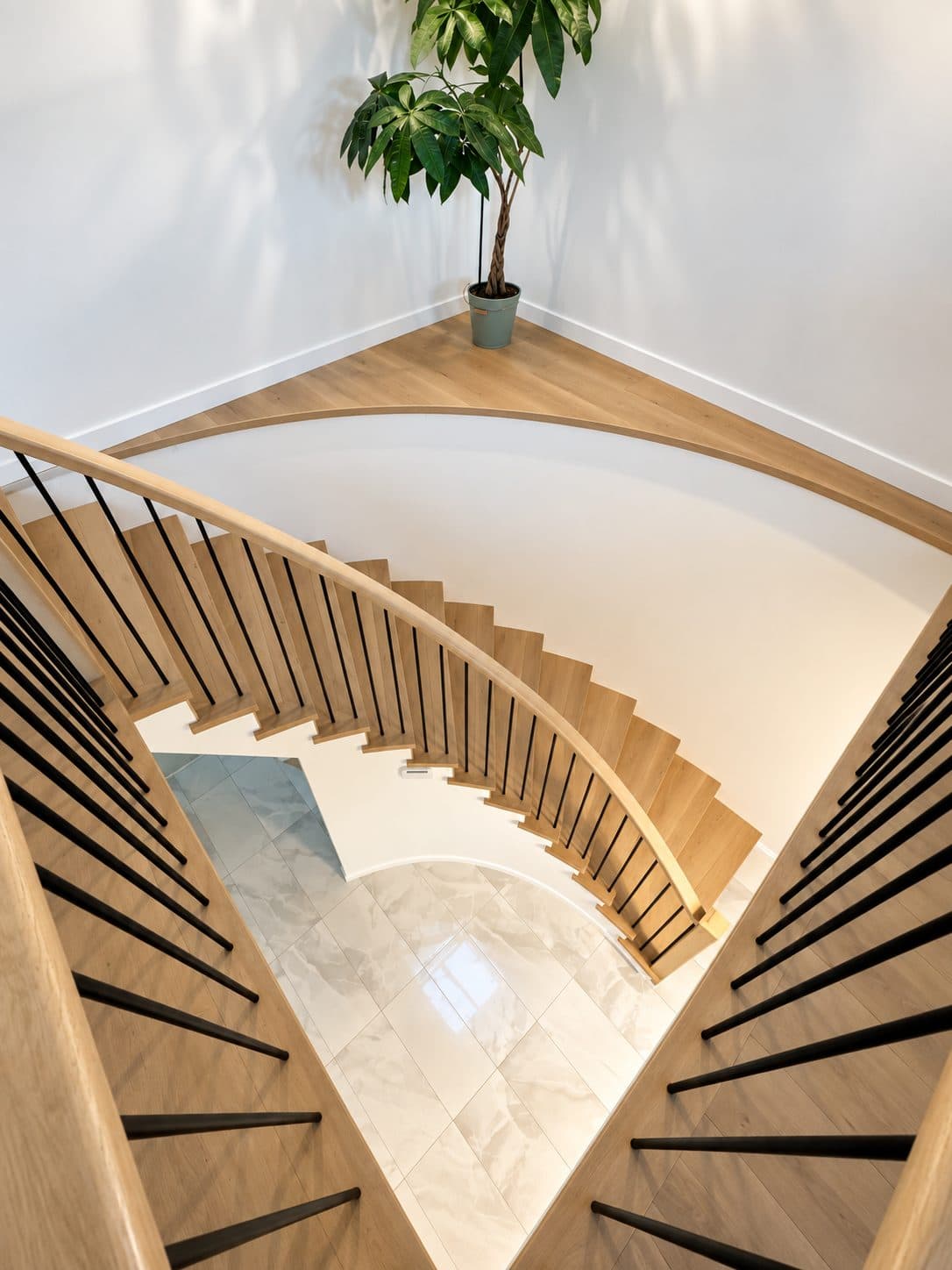 Spiral staircase with light wood treads, seen from above