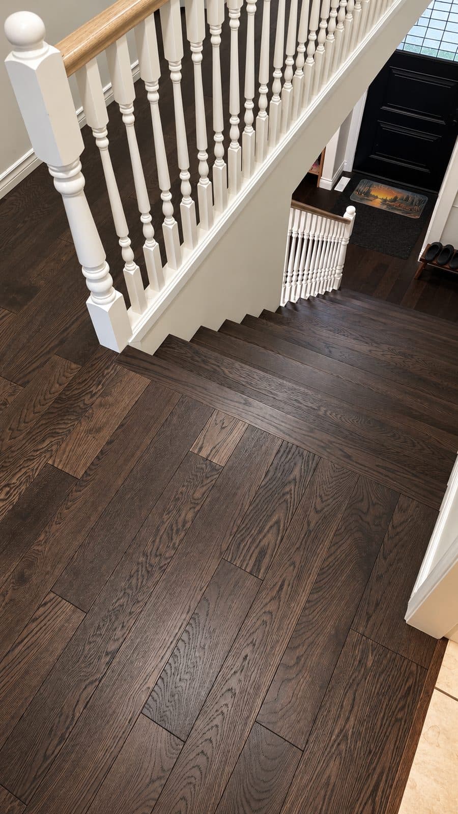 Dark wood floor at the top of a white-spindled staircase