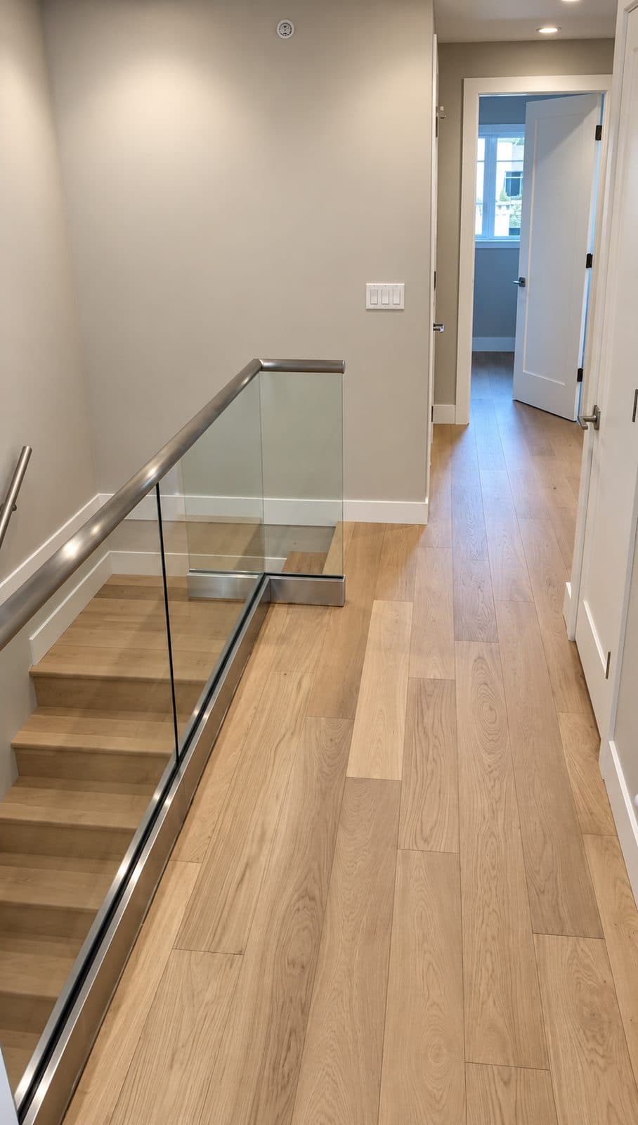 Light wood hallway and stairs behind a glass railing
