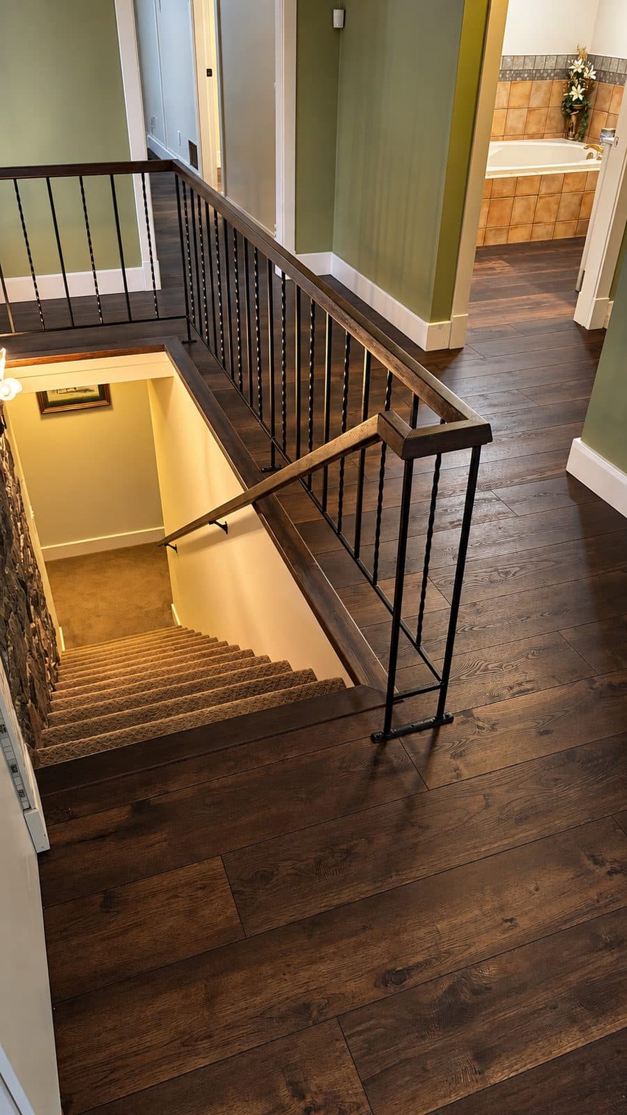 Dark wood floor around a stairwell with iron railings