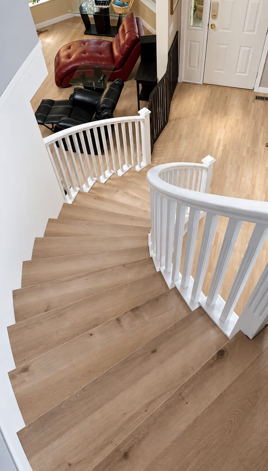 Curved staircase with white railings, seen from above