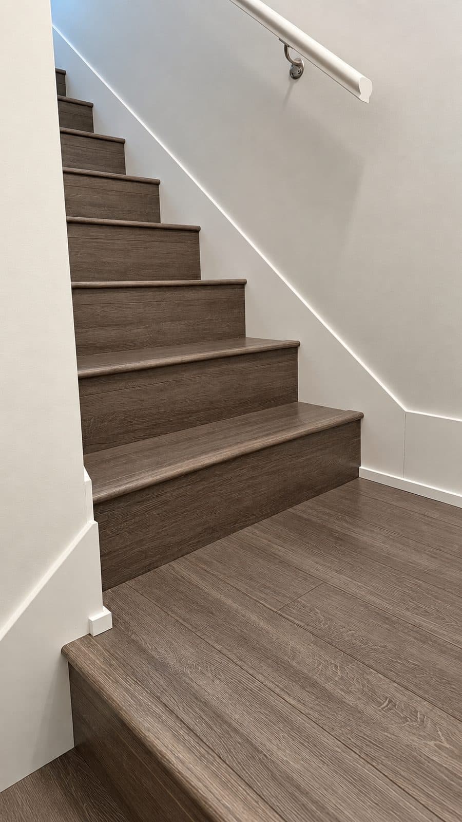 Grey wood staircase with a wall-mounted handrail