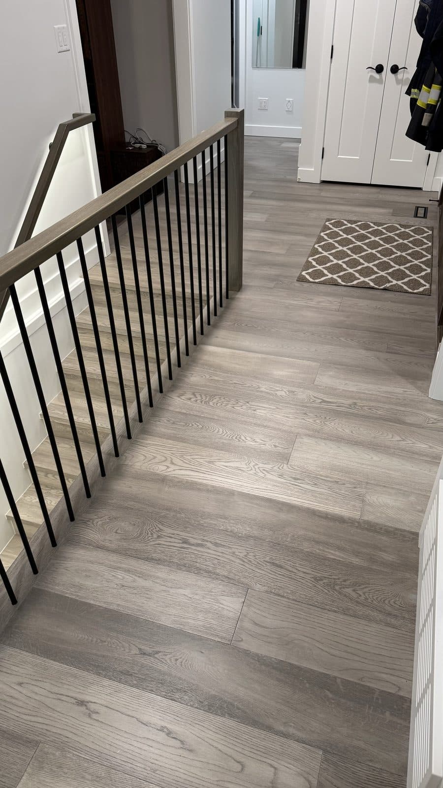 Grey wood floor along a black-spindled railing