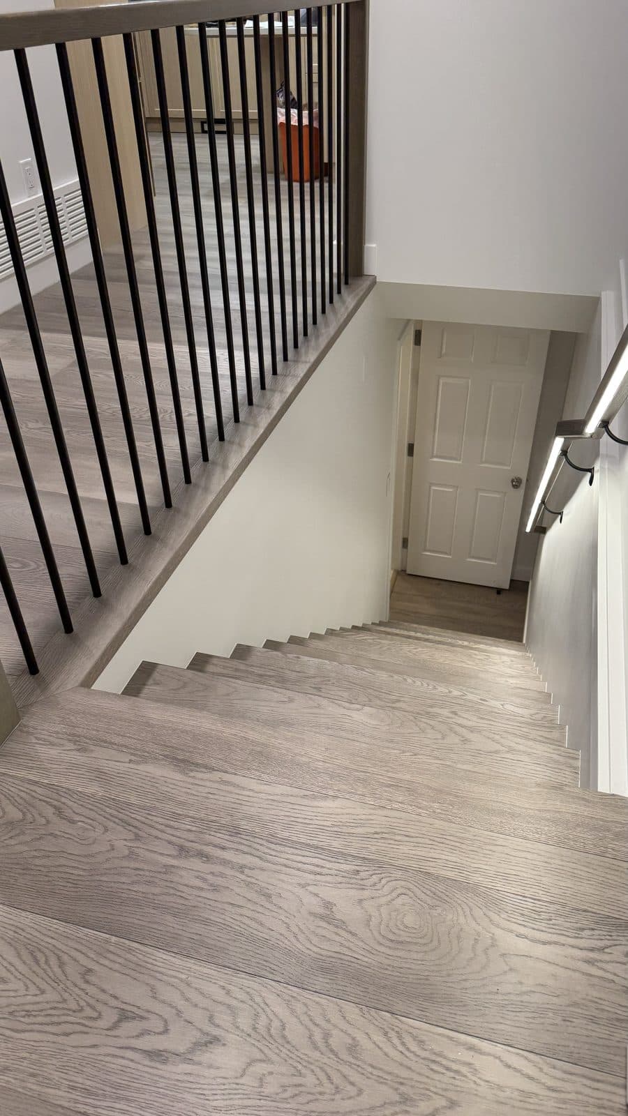 Grey wood stairs leading down past black balusters