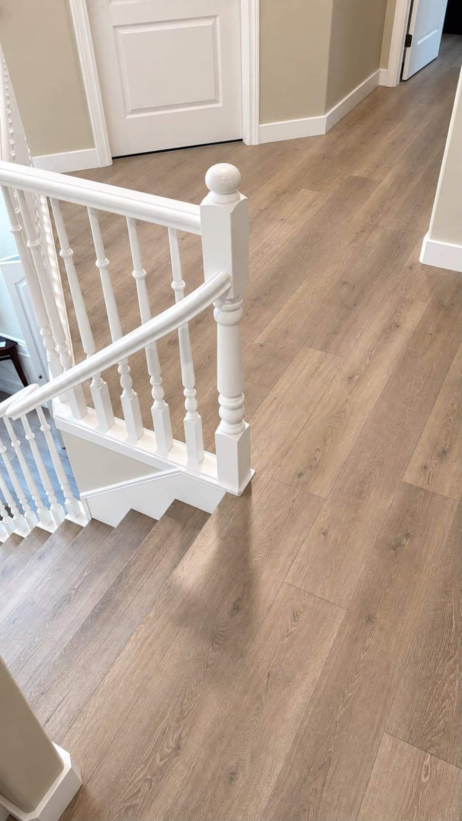 Wide-plank wood-look floor installed through an upstairs hallway and onto the stairs
